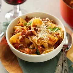En skål med paccheri pasta med en mustig ragu, toppad med riven parmesan. Perfekt för ett mysigt middagsrecept.