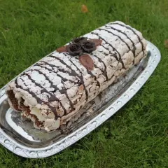 En läcker Budapestrulle med choklad och grädde, dekorerad med chokladrosor och pudersocker. Perfekt för ett sommarfika.