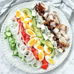 En vacker cobb salad med kyckling, bacon, ägg, avokado, tomat, gurka, lök och blåmögelost.