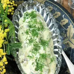 Krämig senapssill i en vacker skål, garnerad med dill. Bredvid syns gula mimosa-blommor. Ett perfekt senapssill recept för festen!
