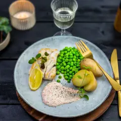 En tallrik med fisk, potatis, ärtor och en krämig romsås. Ett perfekt romsås recept för en härlig middag.