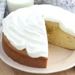 En saftig tres leches-kaka med fluffig grädde. En bit är bortskuren, vilket avslöjar den gyllene kakan.