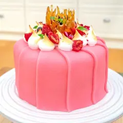 En vacker rosa prinsesstårta med marängtoppar, bär och en karamellkrona. Perfekt för ett prinsesstårta recept!
