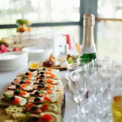 Smörgåsar med lax, rom och citron som tilltugg till bubbel. En flaska champagne står redo bredvid tomma glas.