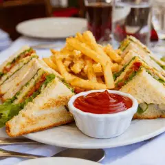 En tallrik med en klassisk club sandwich, pommes frites och ketchup. Perfekt för en lunch!