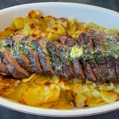Skivat oxfile med örtsmör över krispiga potatisskivor. Ett perfekt oxfile recept för en festmåltid.
