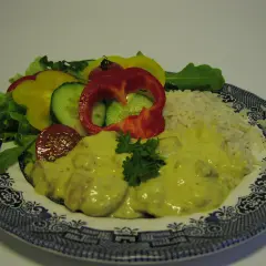 En tallrik med ris, kyckling i krämig currysås, sallad och grönsaker. Ett perfekt currysås recept för en god middag.