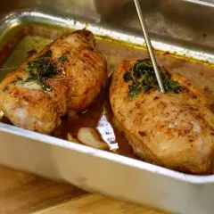Två saftiga kycklingfiléer i ugnsform, redo för ett strimlad kyckling recept. En termometer mäter temperaturen.
