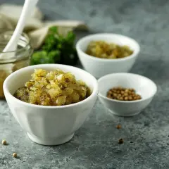 En skål med bostongurka, perfekt för ditt bostongurka recept. Bredvid en burk med gurka och en skål med senapsfrön.