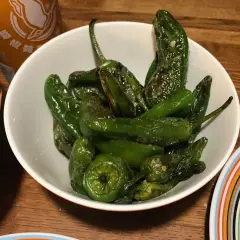 En skål med stekta pimientos de padron, glansiga och gröna, redo att avnjutas.
