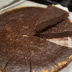 En saftig ica kladdkaka, uppskuren i bitar med en kniv bredvid.