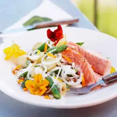 En läcker potatissallad med sparris och lax, dekorerad med ätbara blommor. Perfekt för en somrig lunch utomhus.