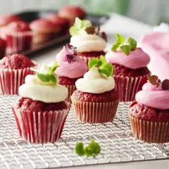 Red velvet cupcakes med fluffig frosting, perfekta för ett cupcakes recept. Garnerade med gröna blad och en rosa sprits.