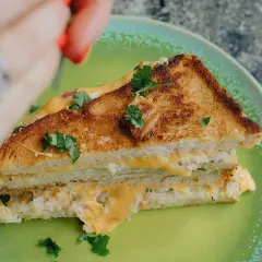 En gyllene, krispig tuna melt med smält ost och färska örter på en grön tallrik.