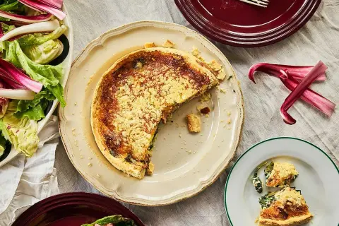 En saftig quiche lorraine med en gyllene skorpa, serverad med en fräsch sallad.