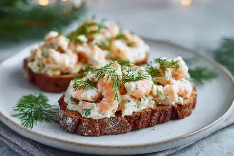 Två toast Skagen på mörkt bröd, toppade med räkor, majonnäs och dill. En klassisk svensk delikatess.