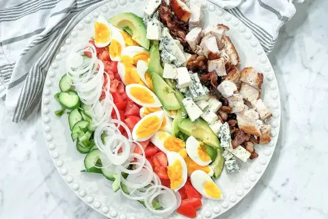 En vacker cobb salad med kyckling, bacon, ägg, avokado, tomat, gurka, lök och blåmögelost.