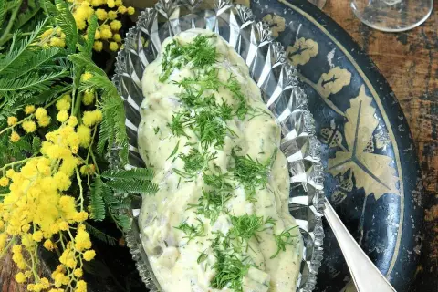 Krämig senapssill i en vacker skål, garnerad med dill. Bredvid syns gula mimosa-blommor. Ett perfekt senapssill recept för festen!