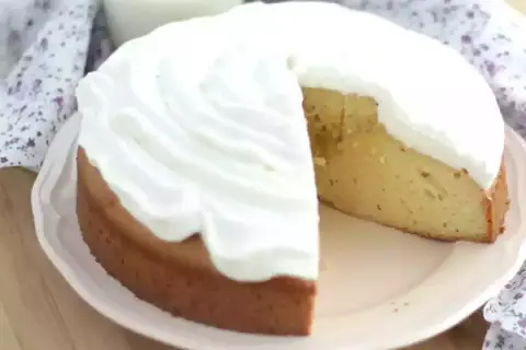 En saftig tres leches-kaka med fluffig grädde. En bit är bortskuren, vilket avslöjar den gyllene kakan.