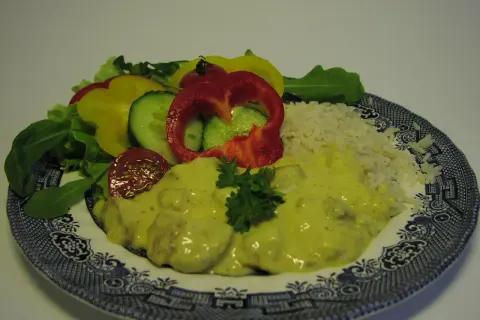 En tallrik med ris, kyckling i krämig currysås, sallad och grönsaker. Ett perfekt currysås recept för en god middag.