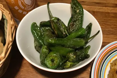 En skål med stekta pimientos de padron, glansiga och gröna, redo att avnjutas.