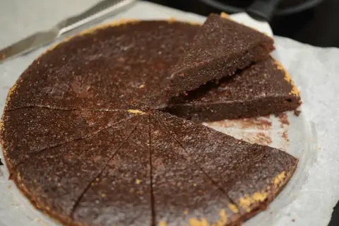 En saftig ica kladdkaka, uppskuren i bitar med en kniv bredvid.