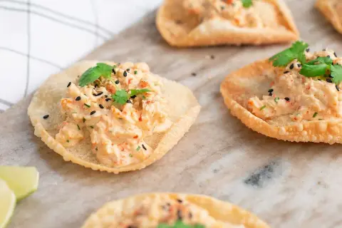 Små, krispiga tortillachips med en krämig topping av räkor och örter, toppade med svarta sesamfrön. Perfekta som enkla tilltugg.