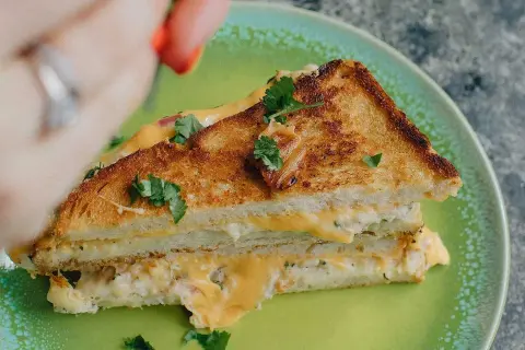 En gyllene, krispig tuna melt med smält ost och färska örter på en grön tallrik.