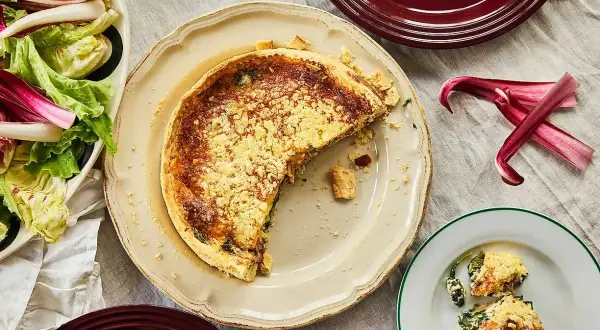 En saftig quiche lorraine med en gyllene skorpa, serverad med en fräsch sallad.