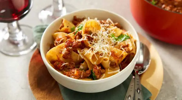 En skål med paccheri pasta med en mustig ragu, toppad med riven parmesan. Perfekt för ett mysigt middagsrecept.