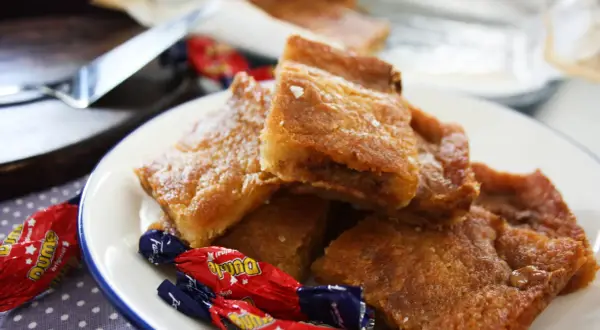Gyllene, krispiga bitar av dumlekakor recept, prydda med lite florsocker och omgivna av Dumle-godis. En härlig syn för alla sötsugna!