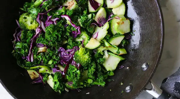 En matig sallad med grönkål, rödkål och broccoli i en wokpanna.