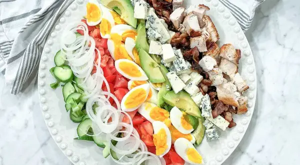 En vacker cobb salad med kyckling, bacon, ägg, avokado, tomat, gurka, lök och blåmögelost.
