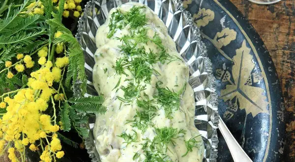 Krämig senapssill i en vacker skål, garnerad med dill. Bredvid syns gula mimosa-blommor. Ett perfekt senapssill recept för festen!