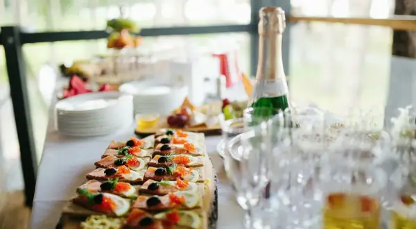 Smörgåsar med lax, rom och citron som tilltugg till bubbel. En flaska champagne står redo bredvid tomma glas.