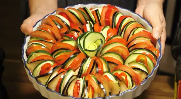 Vacker ratatouille i ugnsform, redo för ugnen. Ett perfekt ratatouille recept med skivade grönsaker som tomat, zucchini och aubergine.