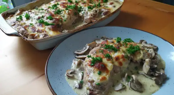 En krämig grekisk pyttipanna med svamp och gratinerad ost, toppad med persilja. Serveras i en ugnsform och på en tallrik.