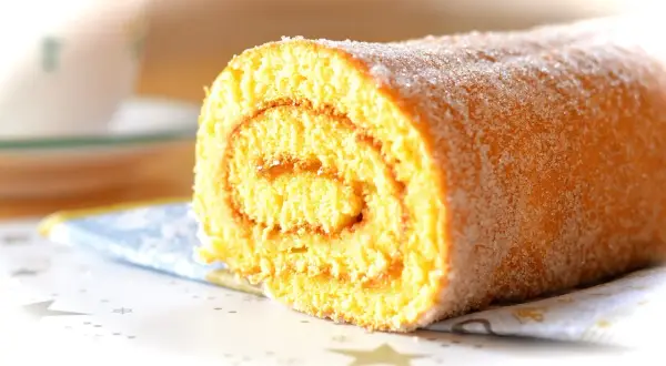 En sockerströdd rulltårta med marmeladfyllning, perfekt för ett enkelt rulltårta recept.