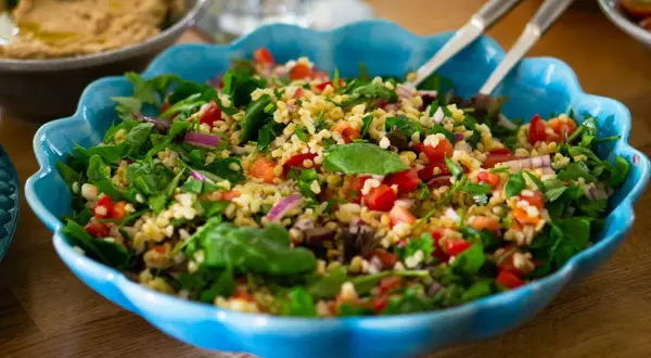 En fräsch tabbouleh med bulgur, tomater, lök och örter i en blå skål. Perfekt för ett lätt lunchrecept.