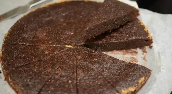 En saftig ica kladdkaka, uppskuren i bitar med en kniv bredvid.