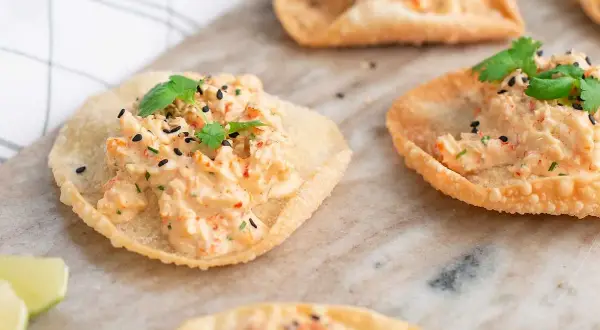 Små, krispiga tortillachips med en krämig topping av räkor och örter, toppade med svarta sesamfrön. Perfekta som enkla tilltugg.