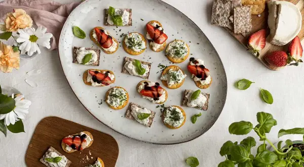 En härlig midsommar buffe med snittar på kex och ost, toppade med jordgubbar och örter.