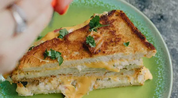 En gyllene, krispig tuna melt med smält ost och färska örter på en grön tallrik.