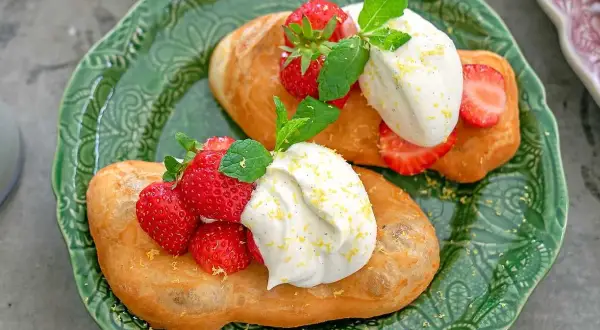 Två friterade langos med grädde, färska jordgubbar och mynta. Ett enkelt langos recept för en härlig fika.