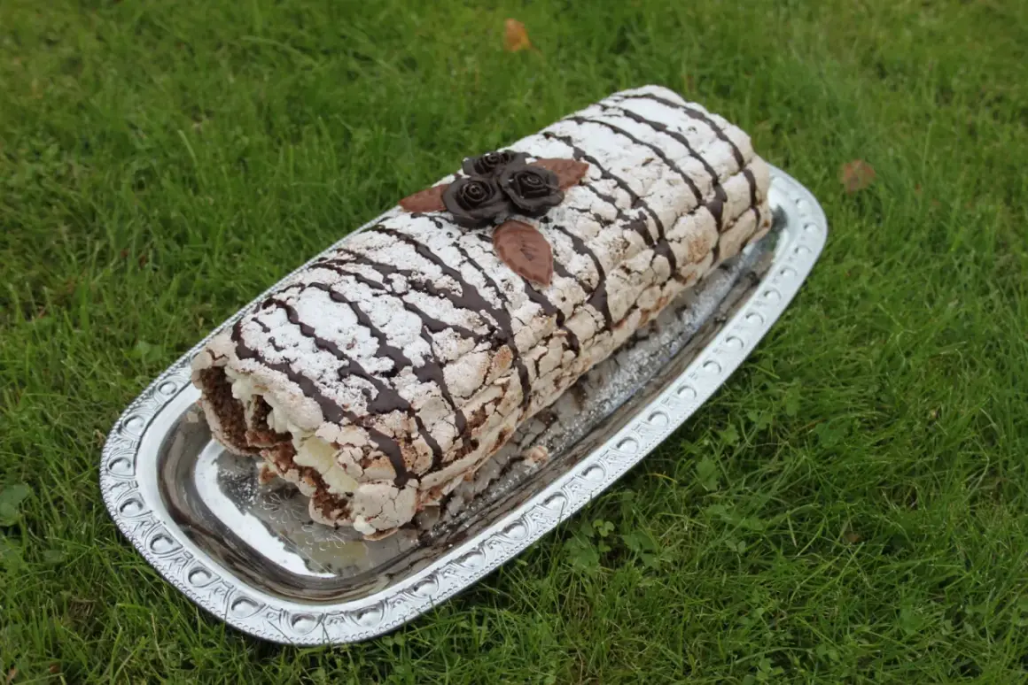 En läcker Budapestrulle med choklad och grädde, dekorerad med chokladrosor och pudersocker. Perfekt för ett sommarfika.