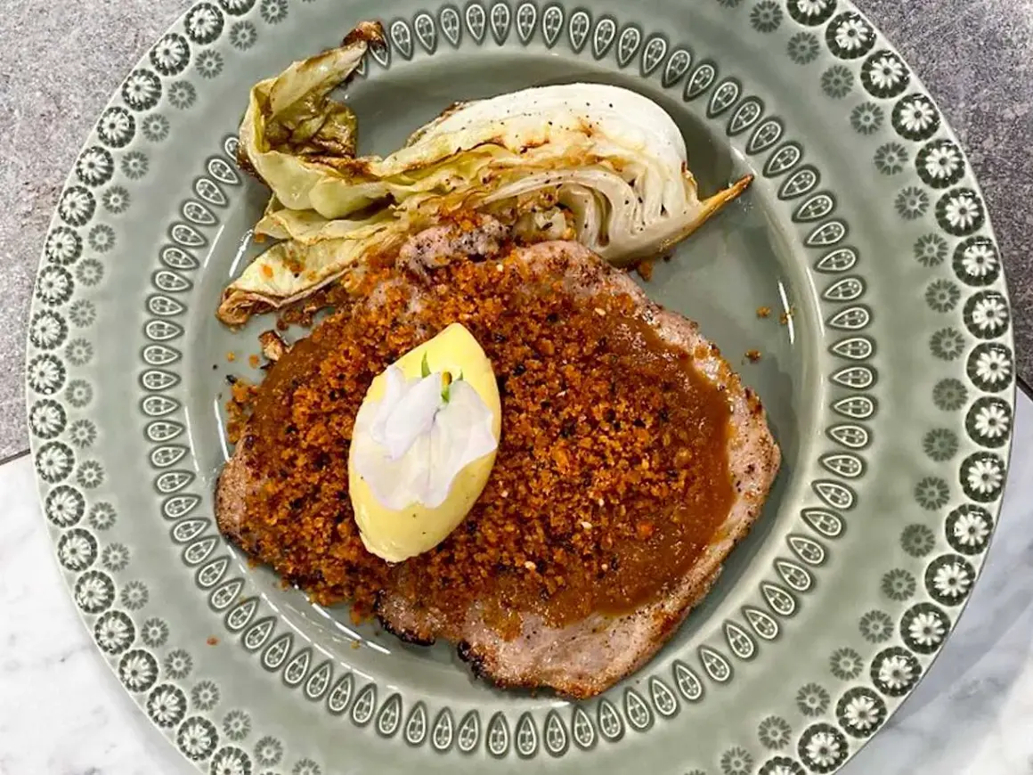 Schnitzel med krispigt täcke och en klick kall sås, garnerad med en blomma. Serveras med ugnsrostad kål.