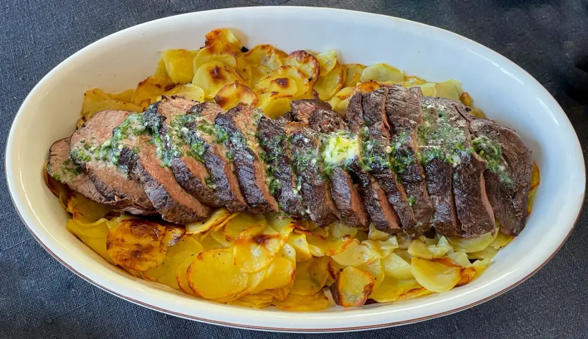 Skivat oxfile med örtsmör över krispiga potatisskivor. Ett perfekt oxfile recept för en festmåltid.