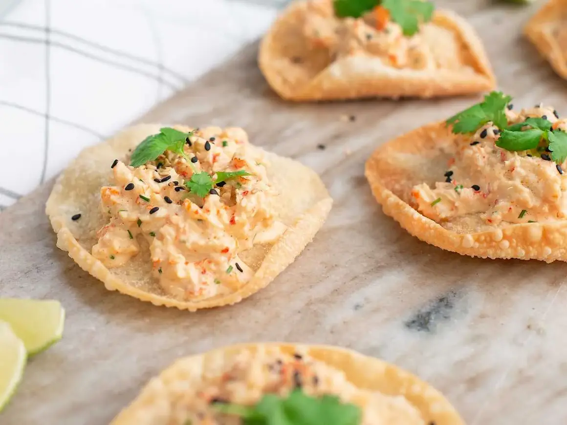 Små, krispiga tortillachips med en krämig topping av räkor och örter, toppade med svarta sesamfrön. Perfekta som enkla tilltugg.