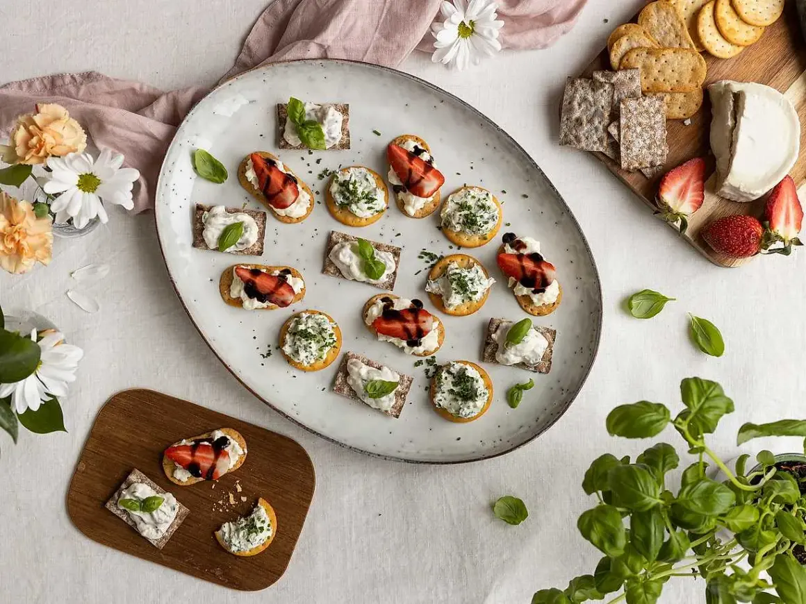 En härlig midsommar buffe med snittar på kex och ost, toppade med jordgubbar och örter.