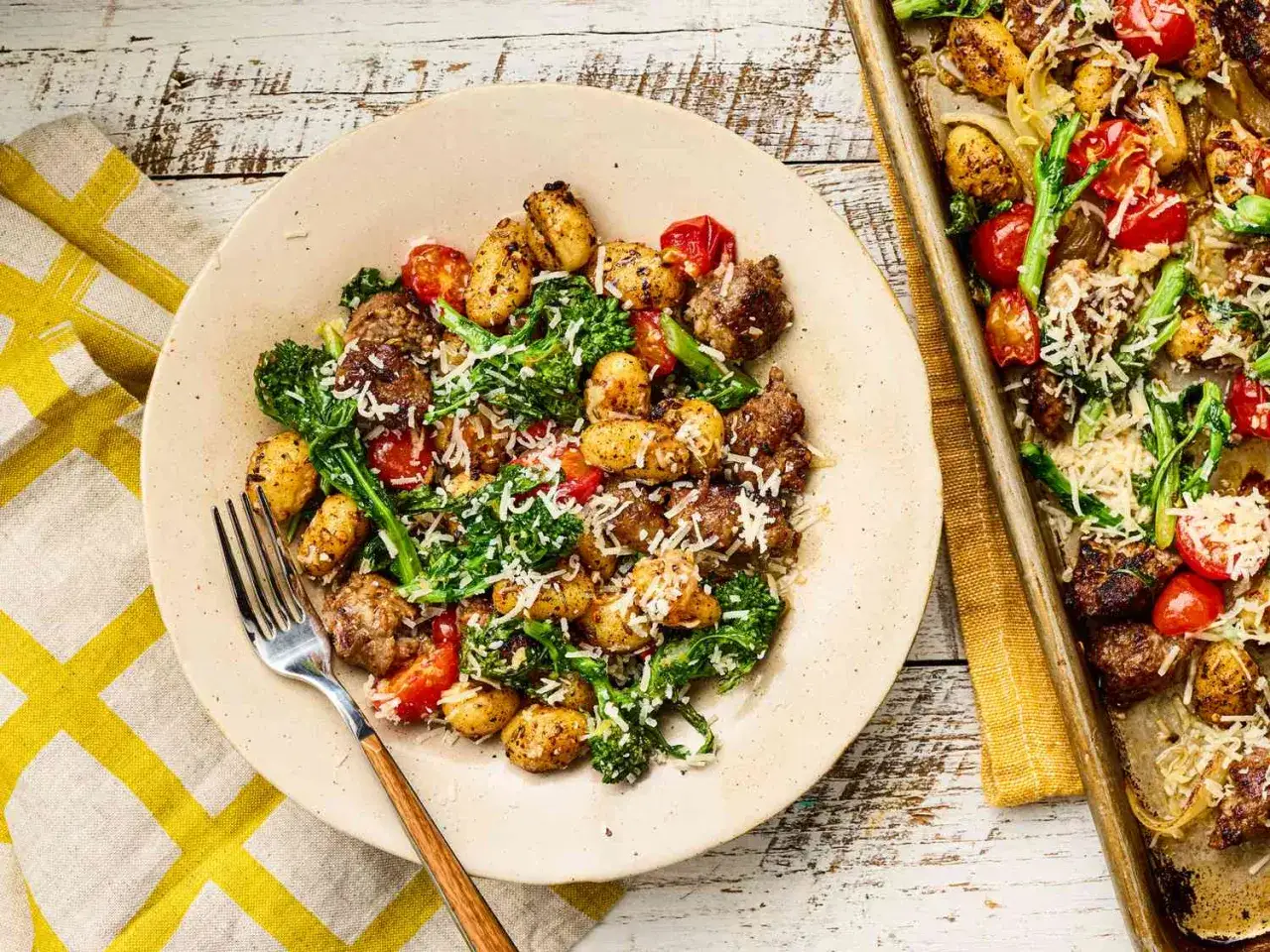 En tallrik med gnocchi, korv, tomater och broccoli, toppad med parmesan. Ett perfekt sommarmiddag recept!